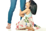 clingy child embracing mother's leg