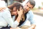 Side view of a muslim man comforting a sad caucasian girl mourning in a train station