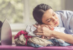 woman sleeping on top of pile of clothes after ironing