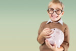 little boy in brown sweatshirt holding a pink piggy bank