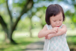 little girl in outdoors surrounded and biten by mosquitoes