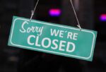 green and white sorry we're closed sign in black bokeh background