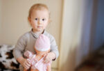 Boy hugging a baby doll in pink dress and a bonnet