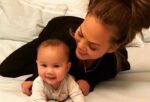 Chrissy Teigen taking care of her baby in white bed