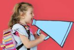 little girl with colorful backpack holding a retro megaphone in red background