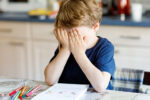 child struggling in school trying to do homework