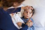 young boy in bed with mum taking his temperature | childrens cold and flu