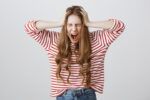 woman with hands on sides of head angry screaming