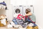 woman sitting on laundry floor with piles of clothes