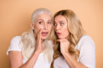 Older woman whispering to younger woman | advice