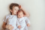 big brother lying next to baby brother happy