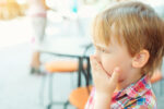 little boy covering his mouth