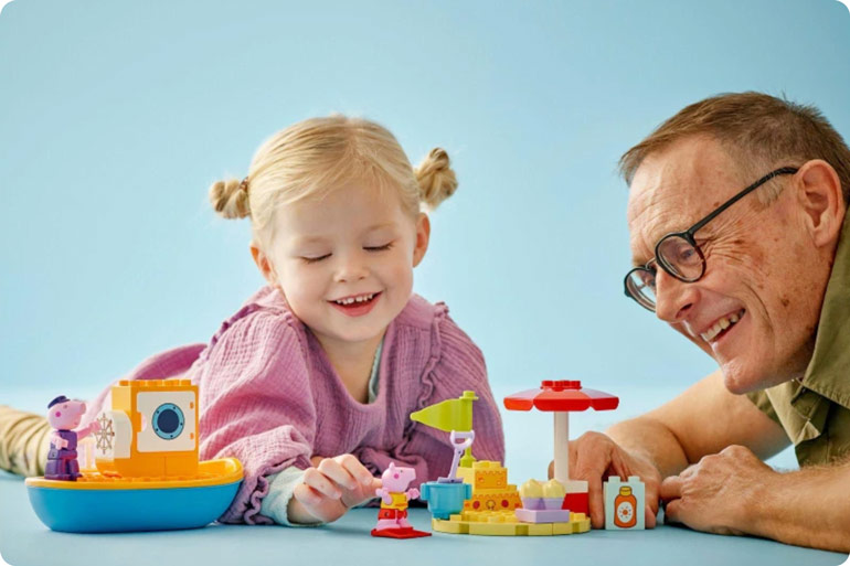 grandparent playing with grandchild and LEGO Duplo
