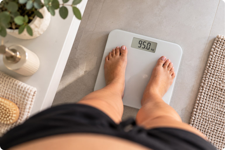 woman standing on bathroom scales after her mounjaro first month